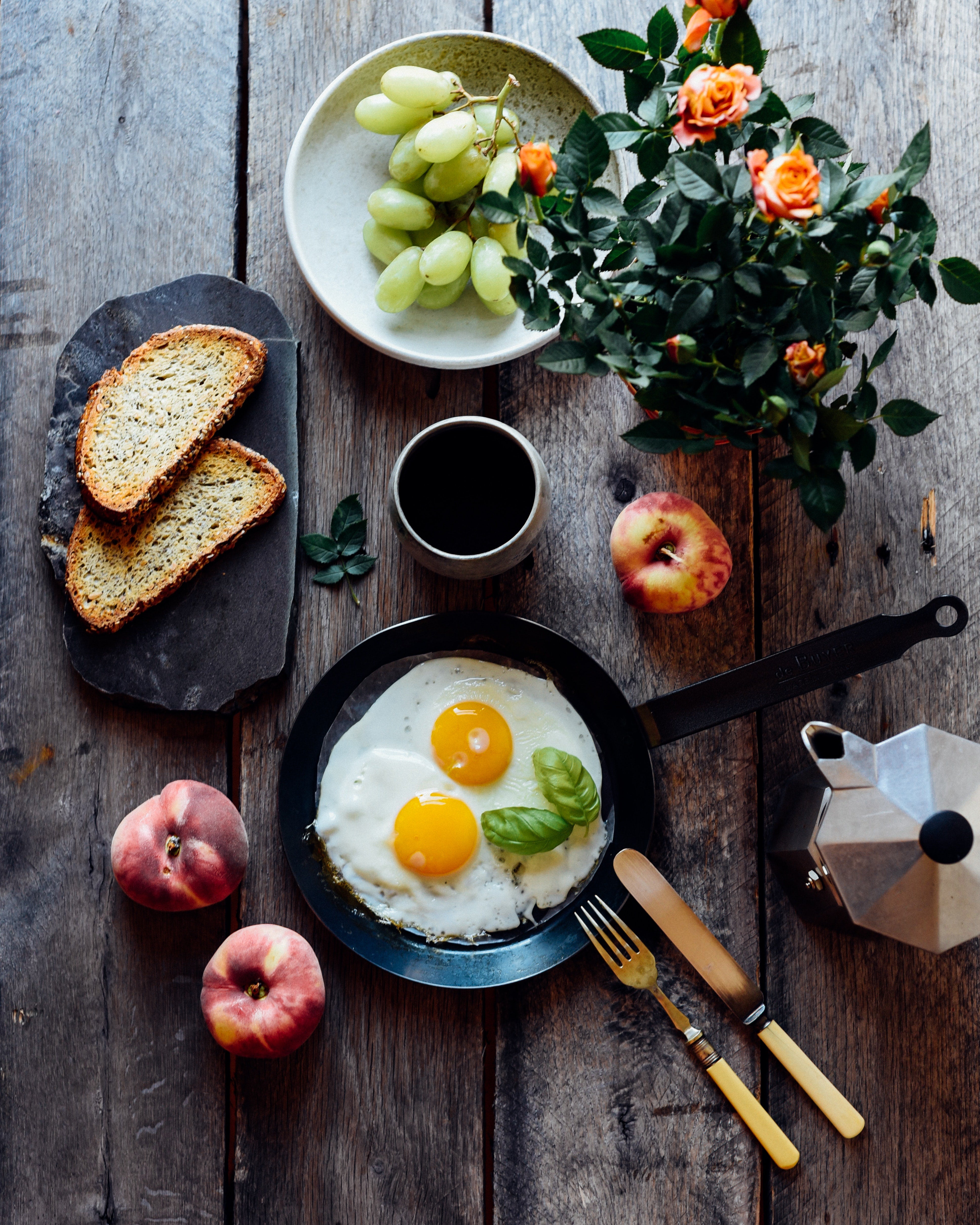 A spread of eggs, grapes, bread, and peaches on a wooden table