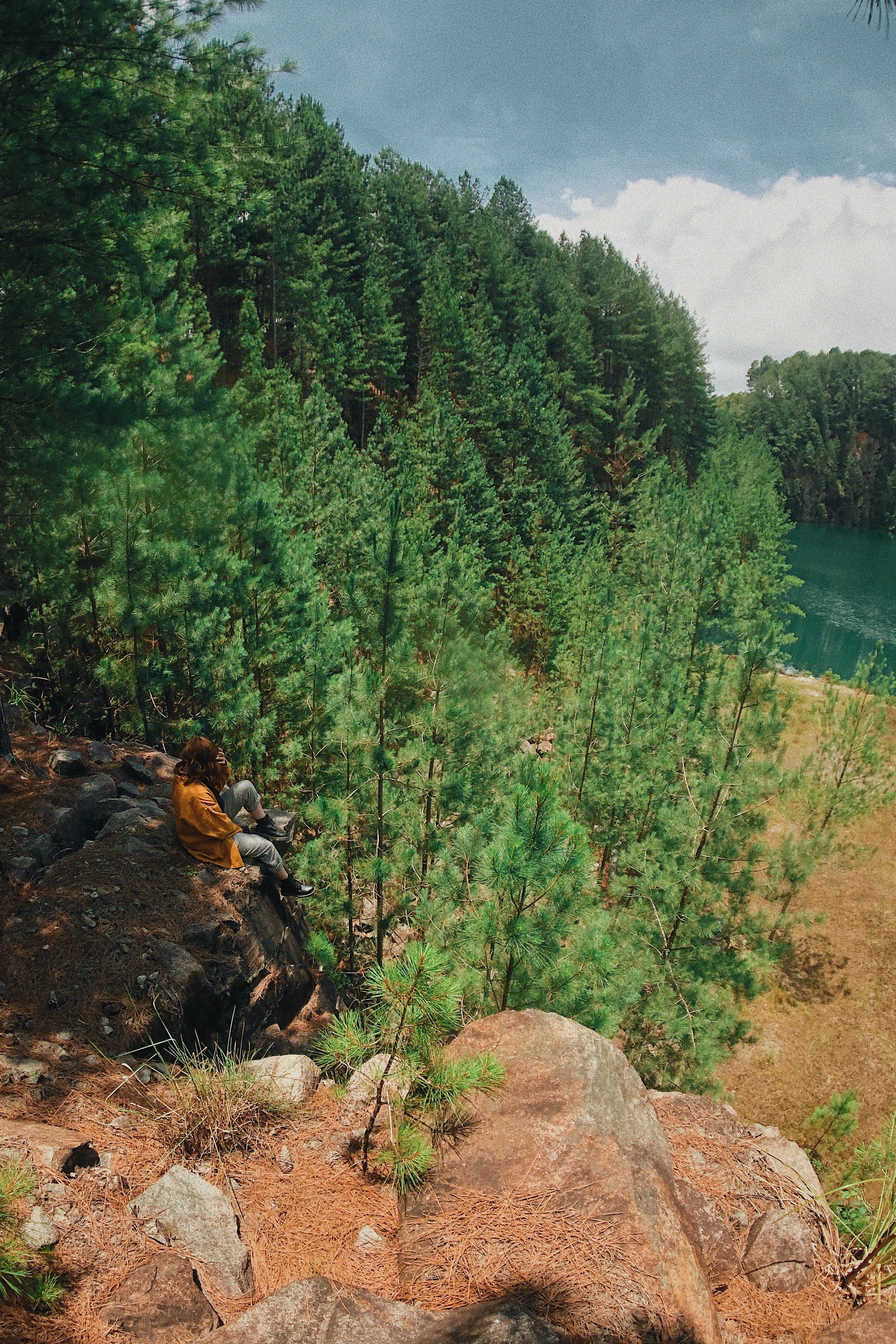 Hiker resting on a cliff overlooking a lake and forest