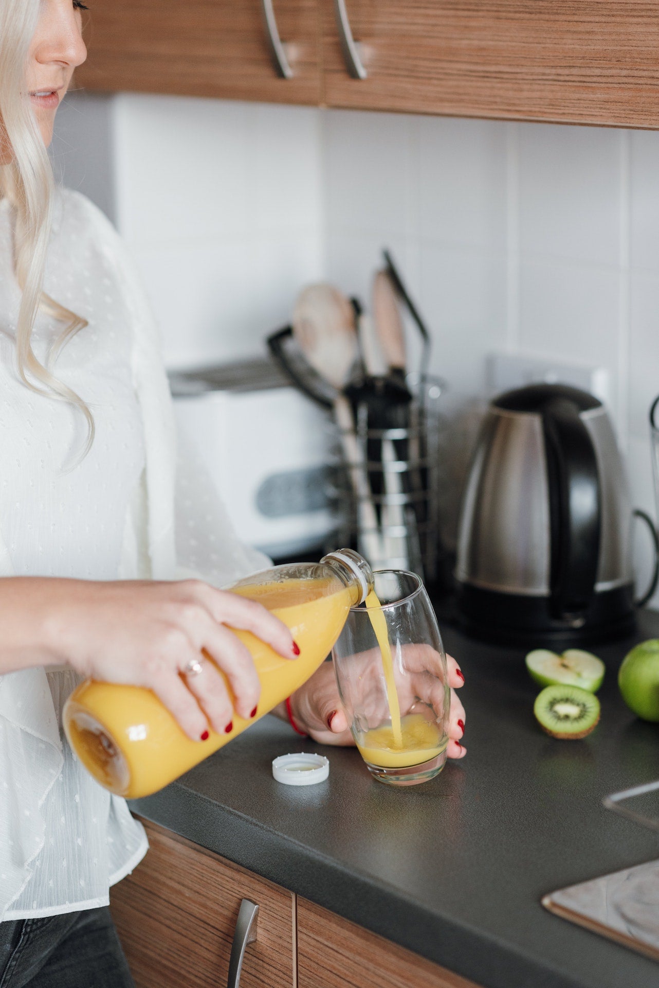 Woman pouring orange juice into cup in a kitchen