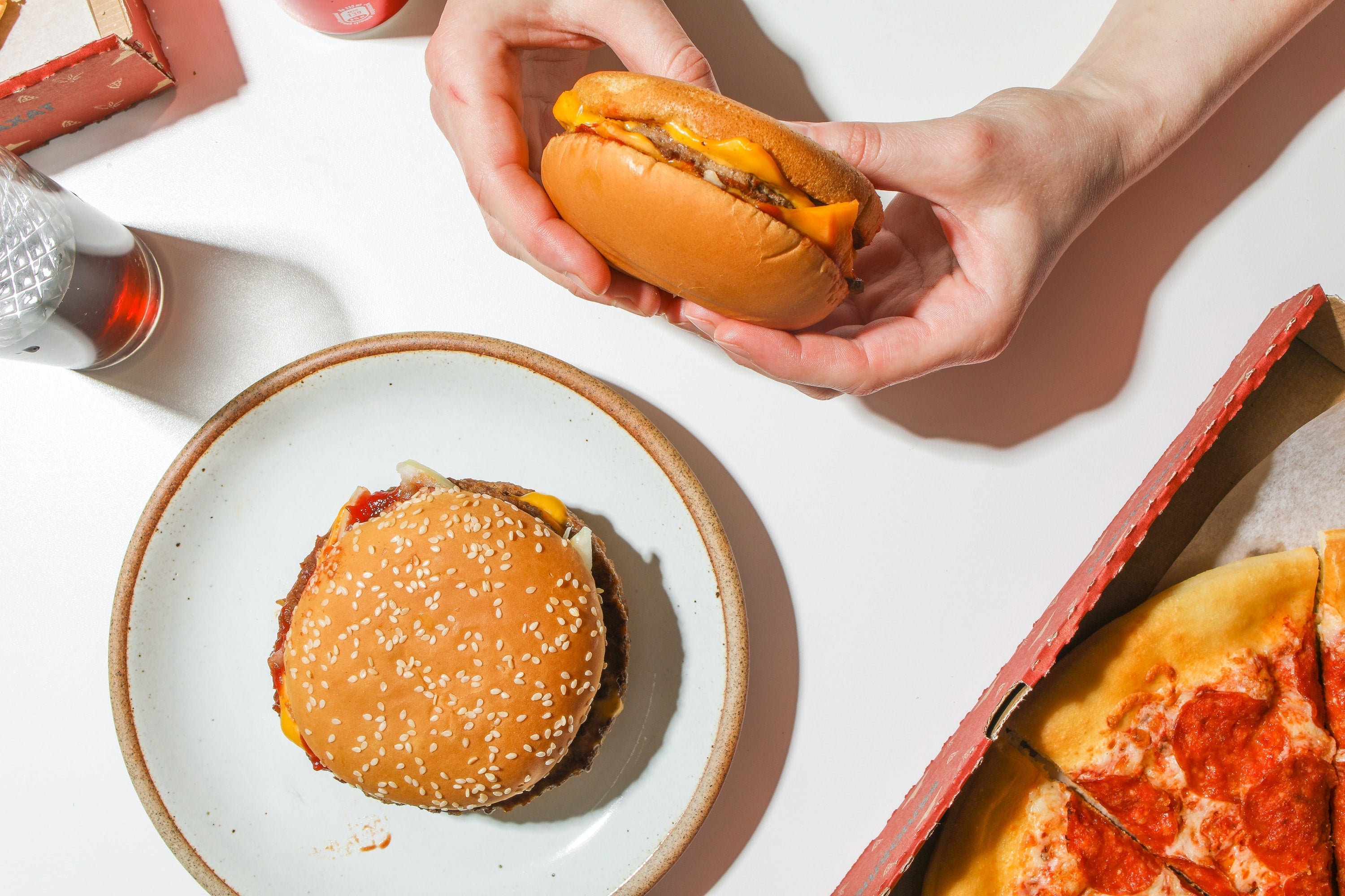 A person holding a burger on a spread of junk food