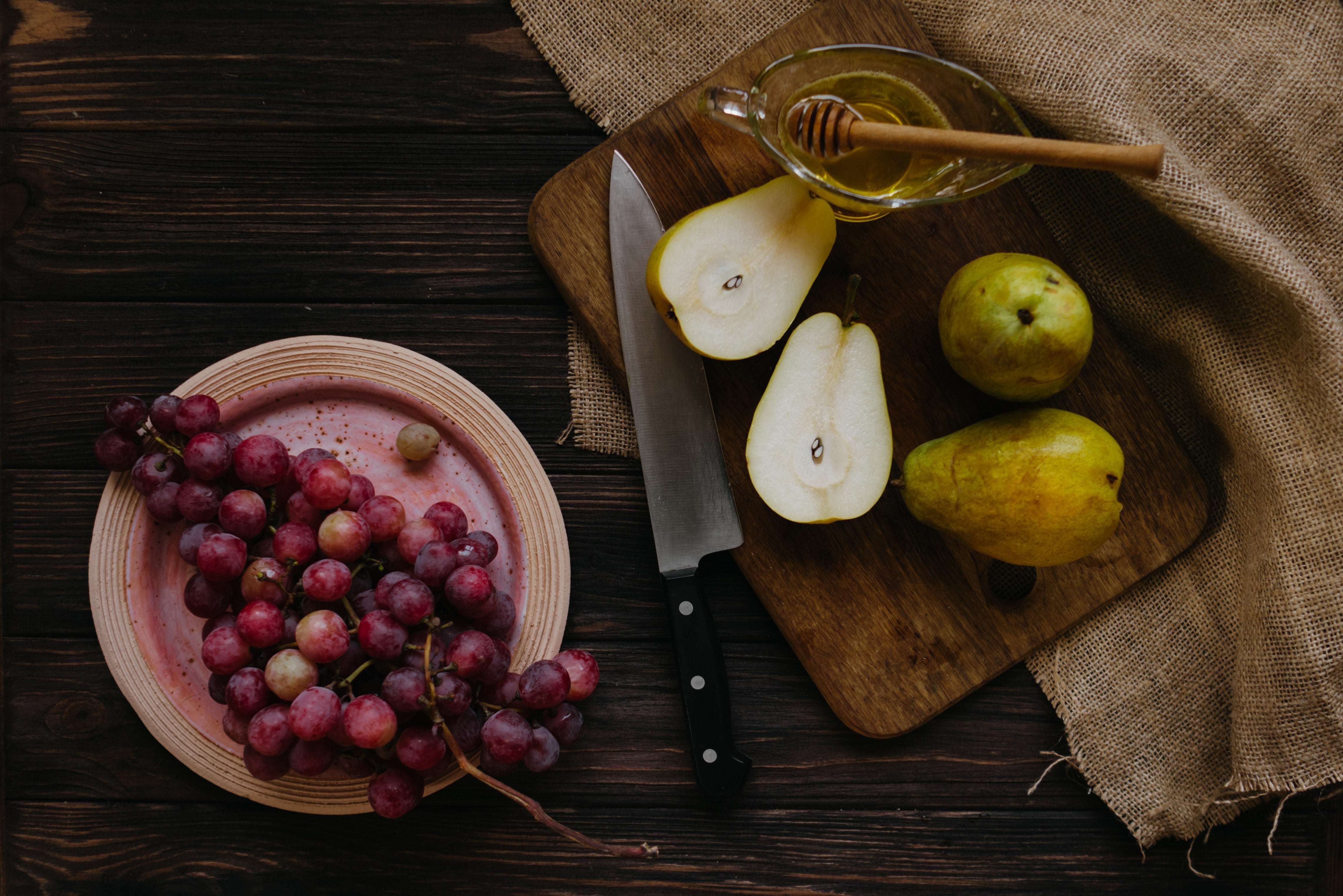 Pears, honey, and grapes on a wooden table