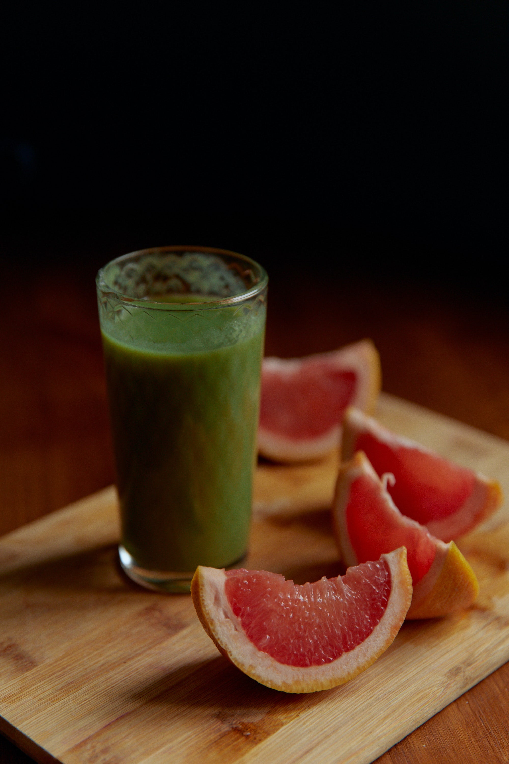 A green smoothie surrounded by grapefruit slices