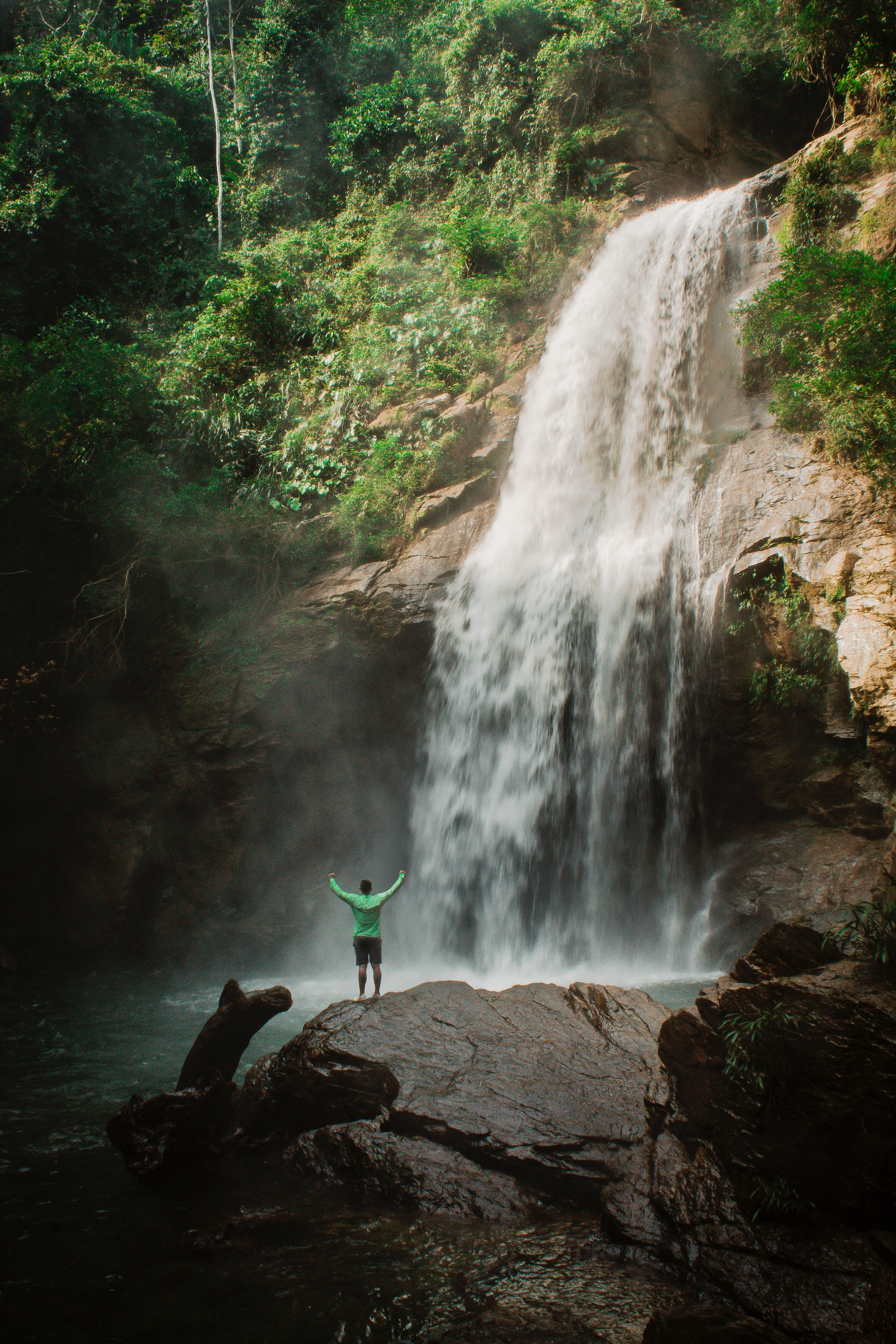 Man on a hike posing in front of a waterfall
