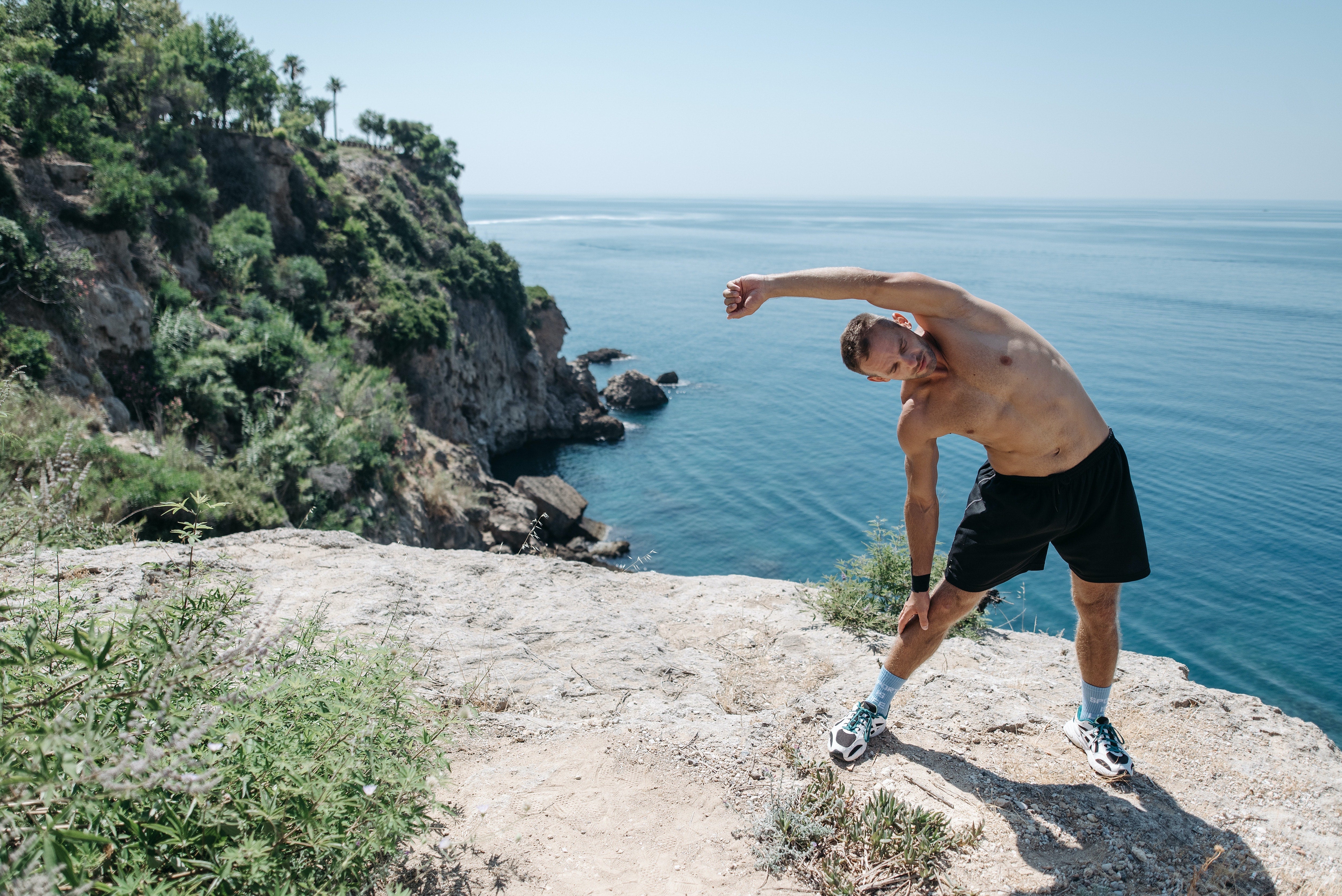 Man stretching on a cliff overlooking the ocean