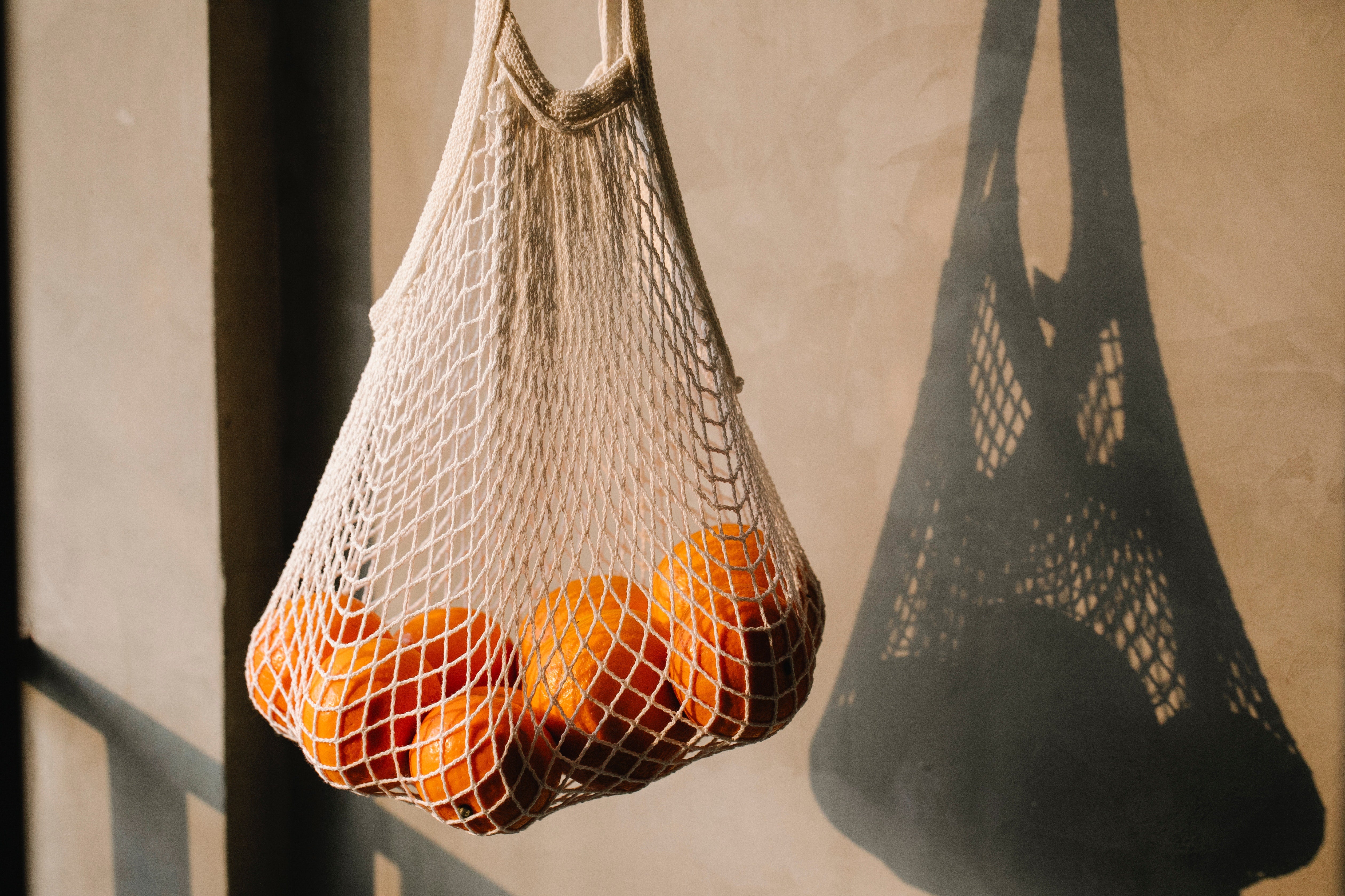 A mesh grocery bag full of oranges